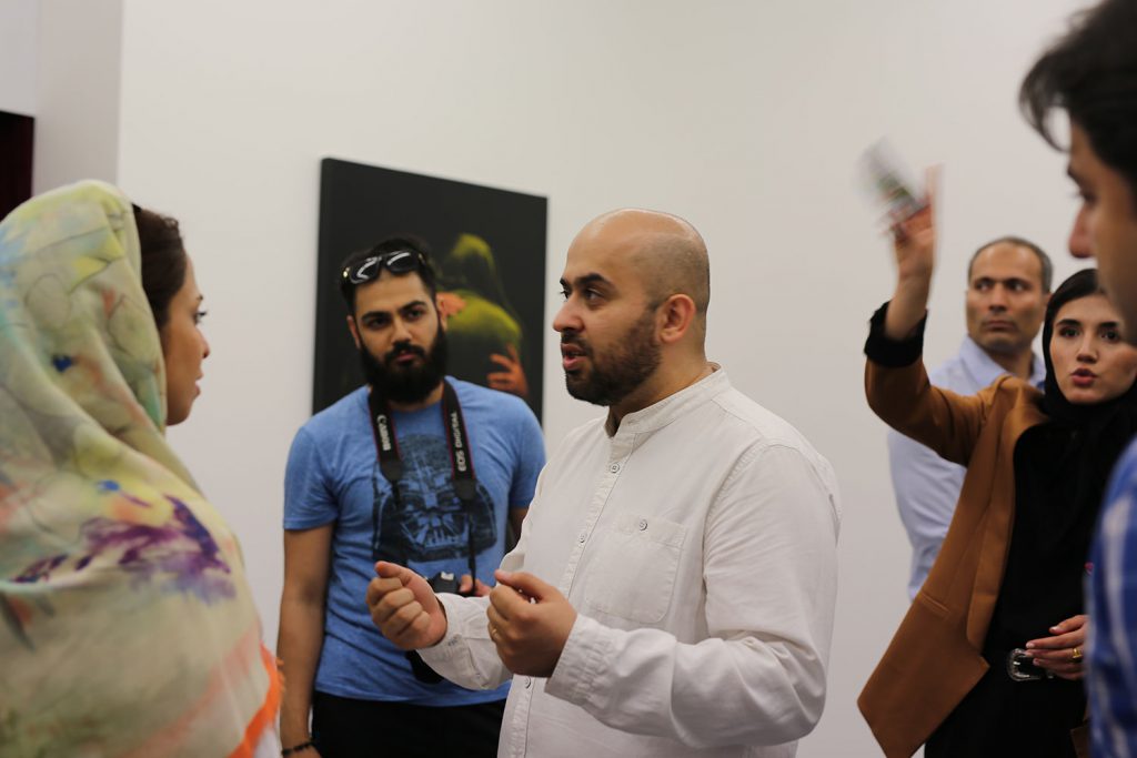 Ali Sabouki is talking with people in his exhibition